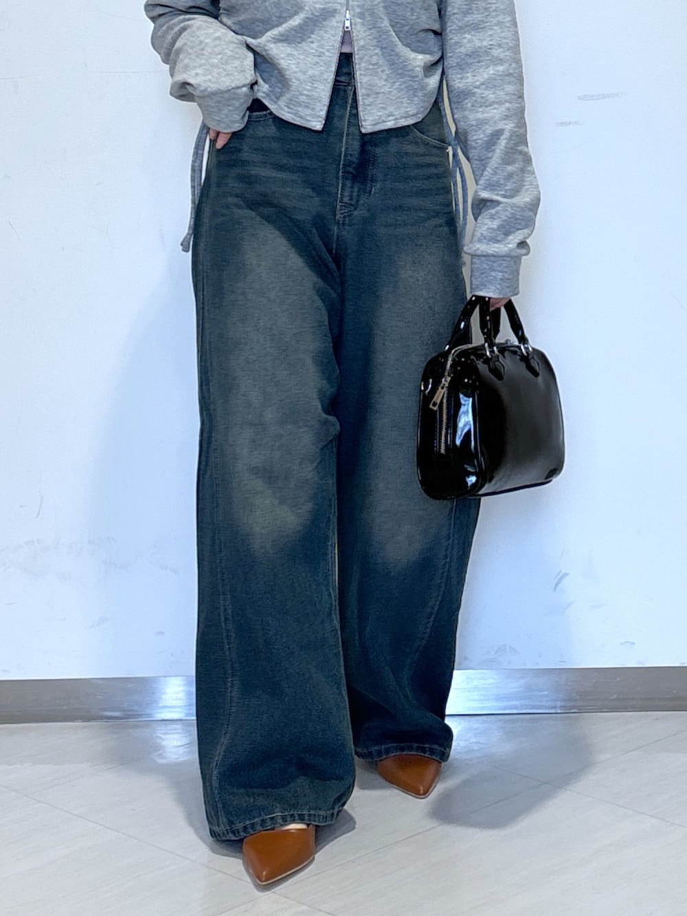 グレー系のパーカー、ブルー系のデニムパンツ、ブラック系のショルダーバッグを着用したレディースの春コーディネートの4枚目の写真