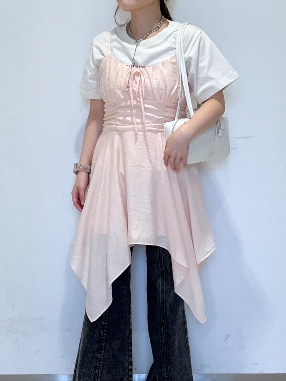ピンク系のワンピース、ホワイト系のTシャツ/カットソー、ホワイト系のショルダーバッグを着用したレディースの春コーディネートの4枚目の写真