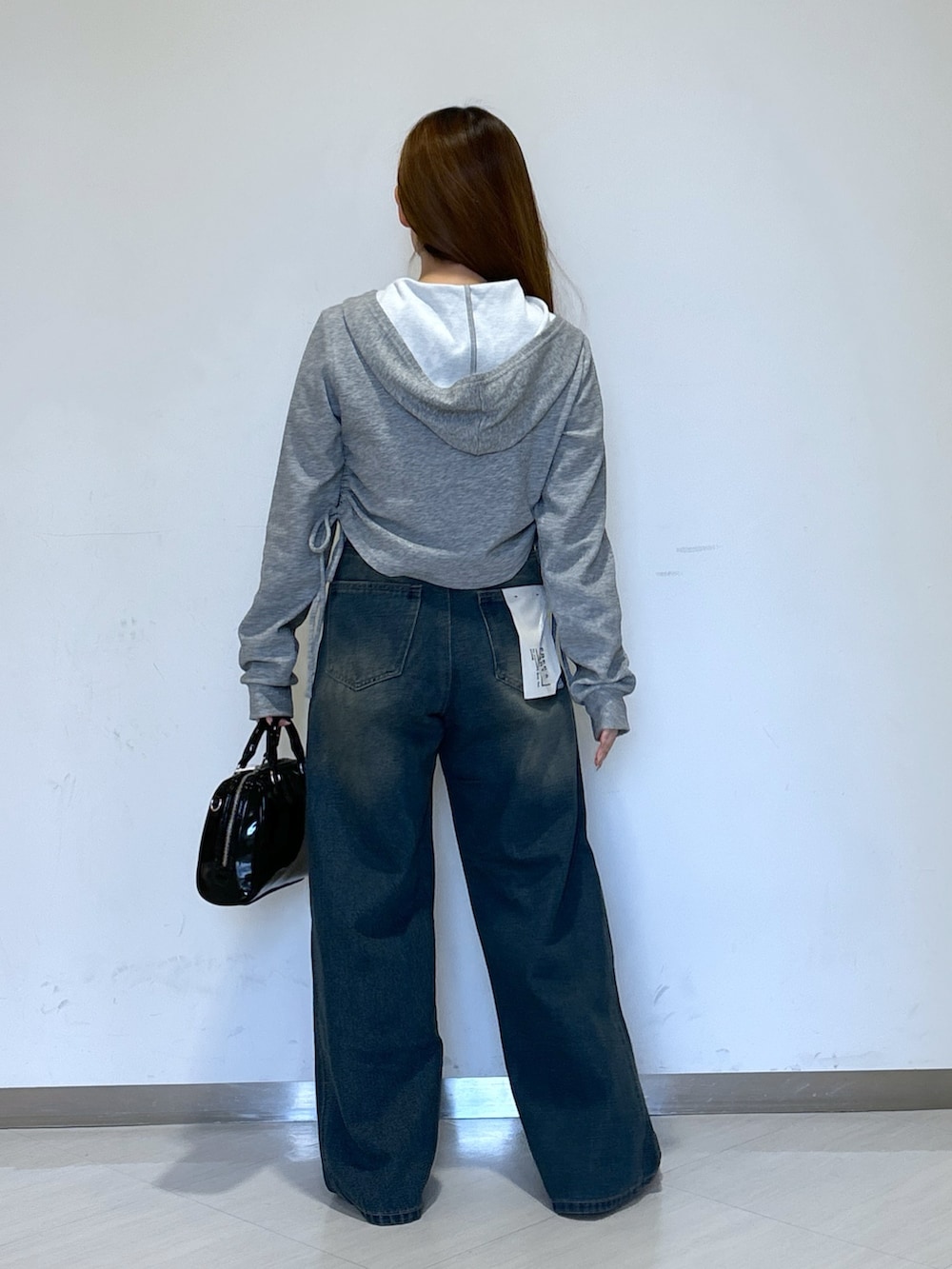 グレー系のパーカー、ブルー系のデニムパンツ、ブラック系のショルダーバッグを着用したレディースの春コーディネートの3枚目の写真