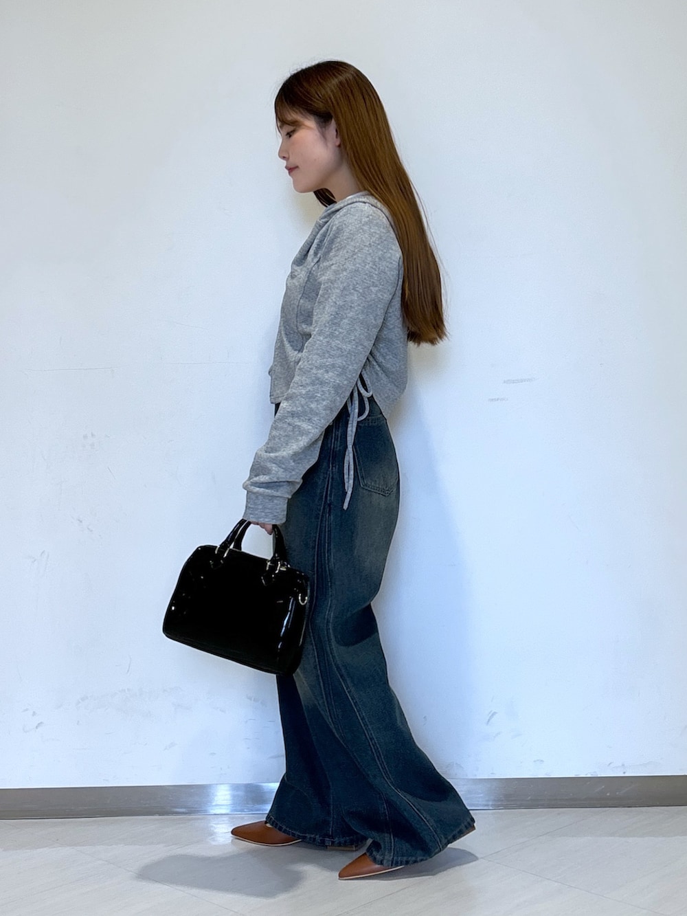 グレー系のパーカー、ブルー系のデニムパンツ、ブラック系のショルダーバッグを着用したレディースの春コーディネートの2枚目の写真