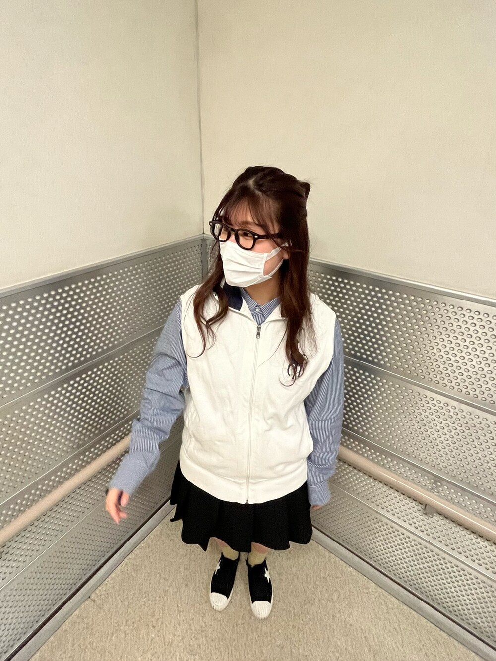 ブラック系のスカート、ホワイト系のベスト、ブルー系のシャツ/ブラウスを着用したレディースの春コーディネートの2枚目の写真