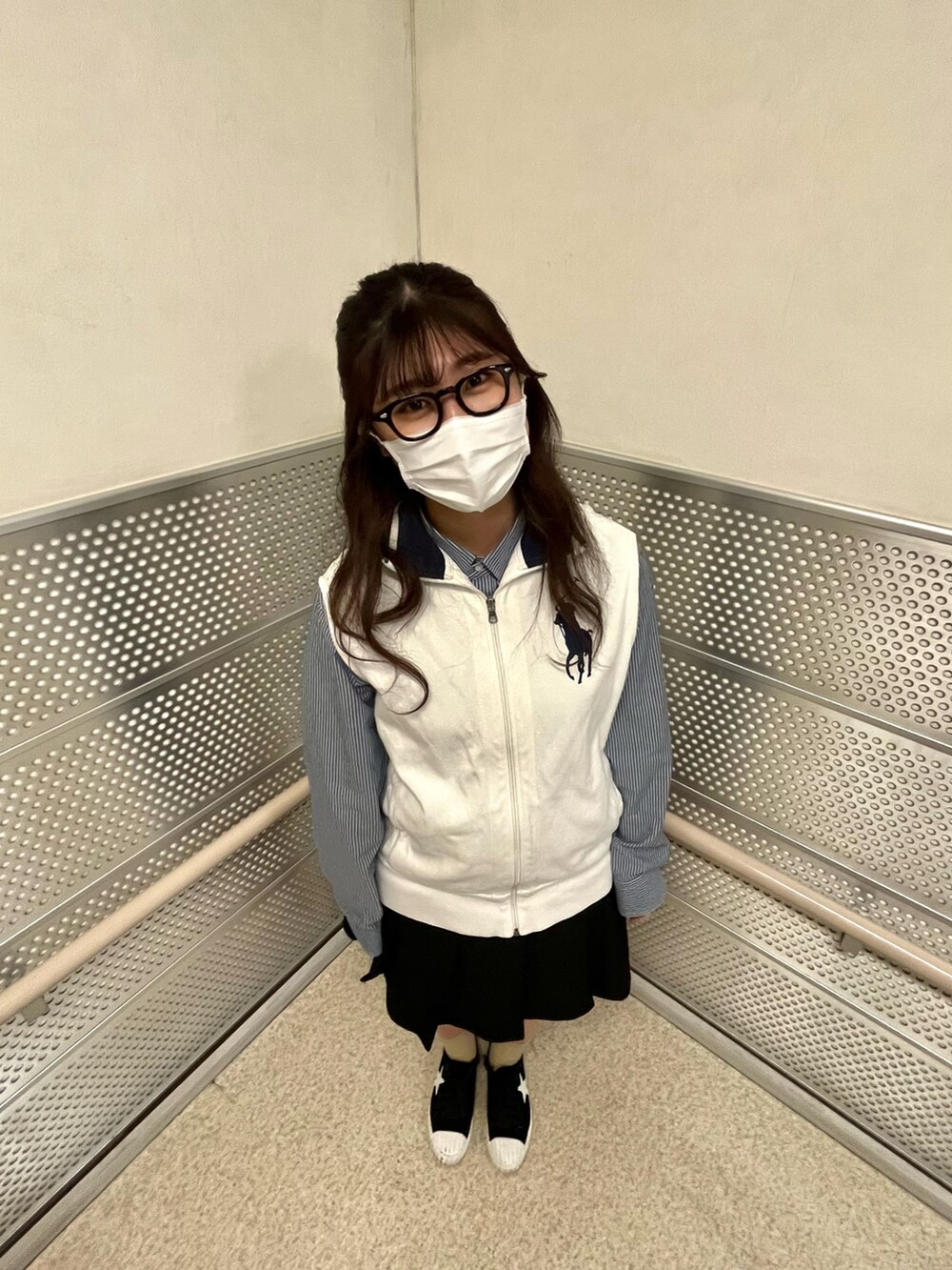 ブラック系のスカート、ホワイト系のベスト、ブルー系のシャツ/ブラウスを着用したレディースの春コーディネートの3枚目の写真