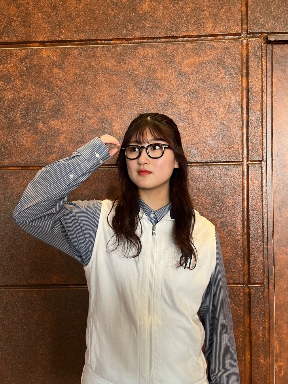 ブラック系のスカート、ホワイト系のベスト、ブルー系のシャツ/ブラウスを着用したレディースの春コーディネートの5枚目の写真