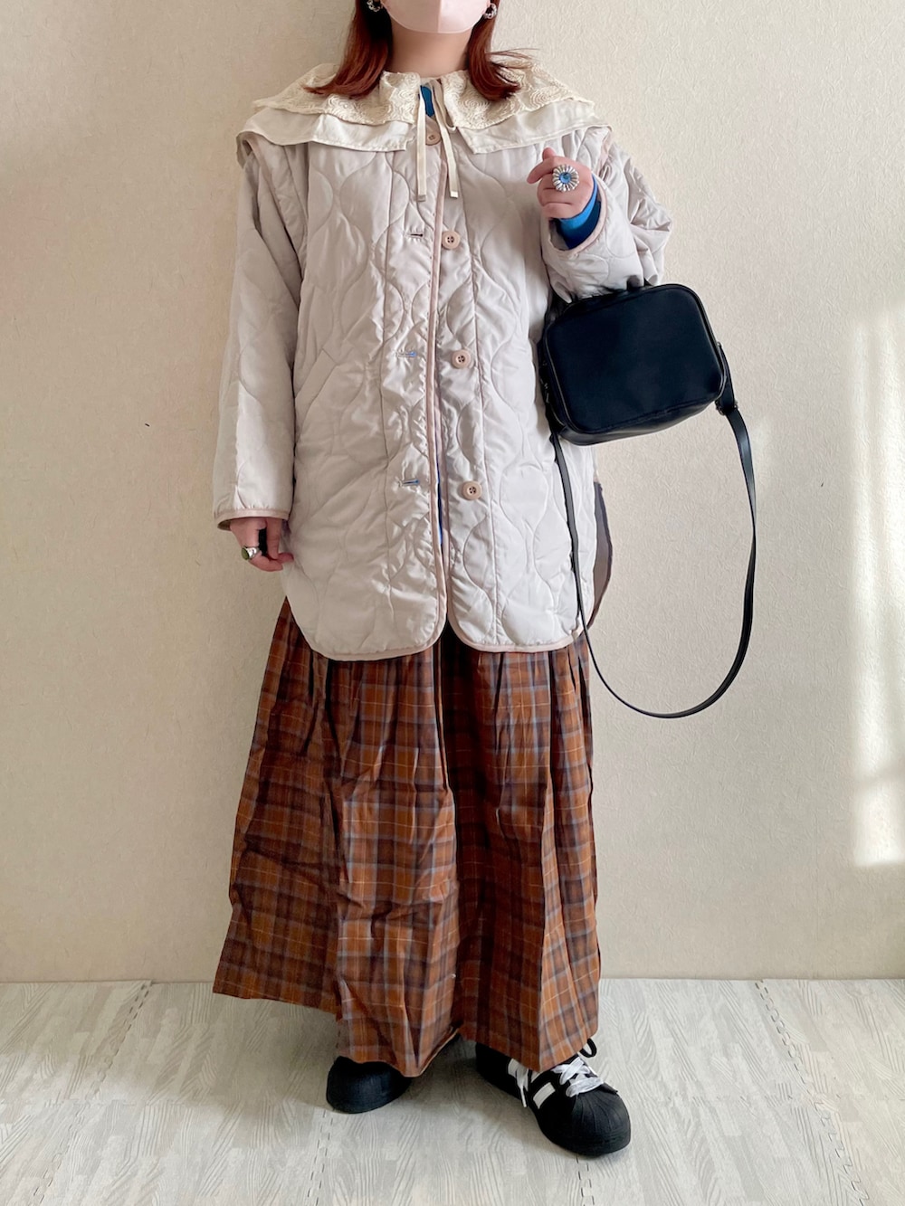 ブラウン系のスカート、ブルー系のスウェット、ブラック系のボストンバッグを着用したレディースの冬コーディネートの2枚目の写真