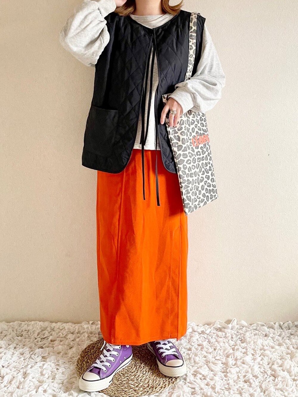 グリーン系のベスト、ホワイト系のトートバッグ、オレンジ系のスカートを着用したレディースの秋コーディネートの2枚目の写真