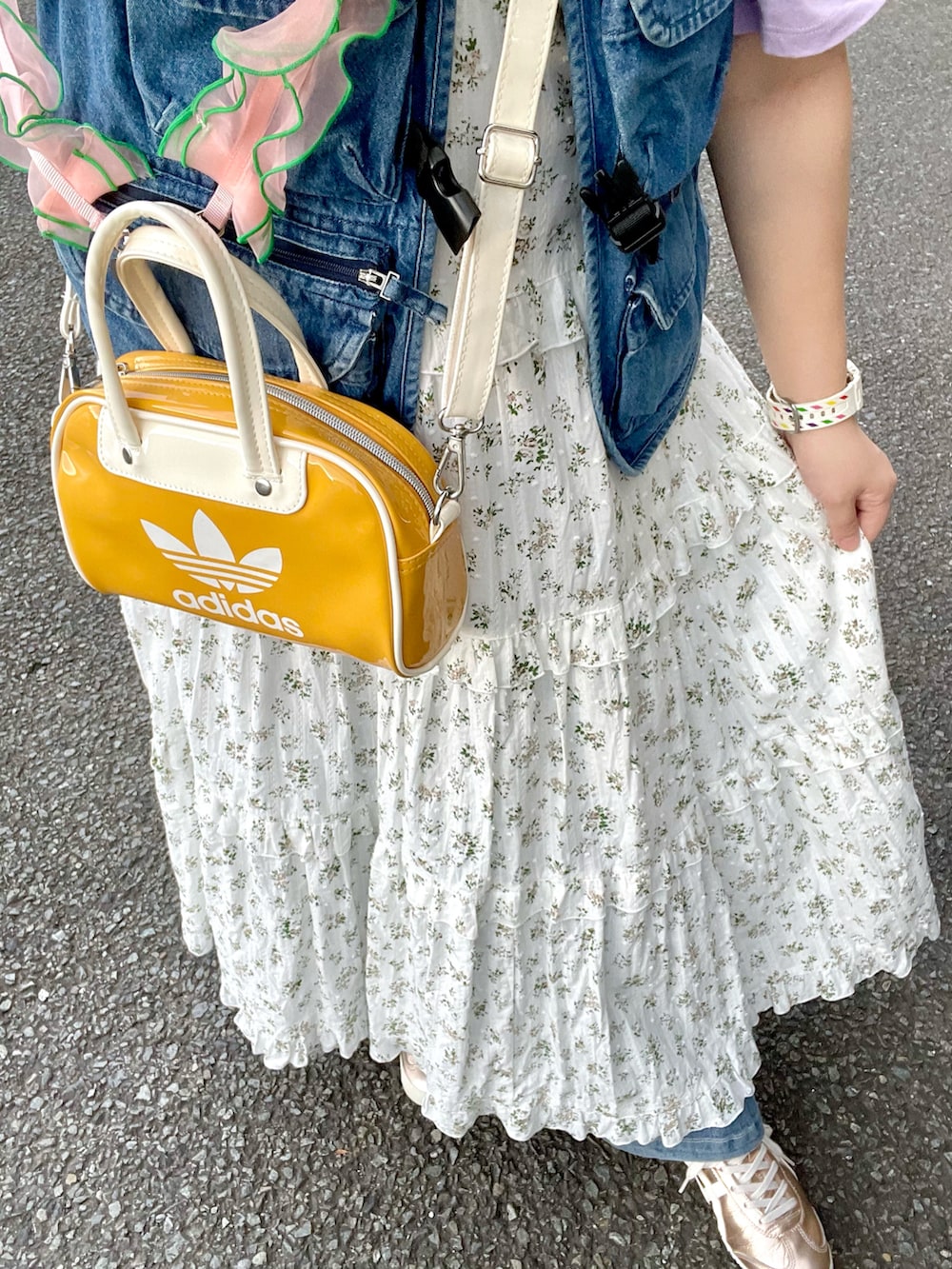 イエロー系のショルダーバッグ、ゴールド系のスニーカー、ホワイト系のワンピースを着用したレディースの秋コーディネートの3枚目の写真