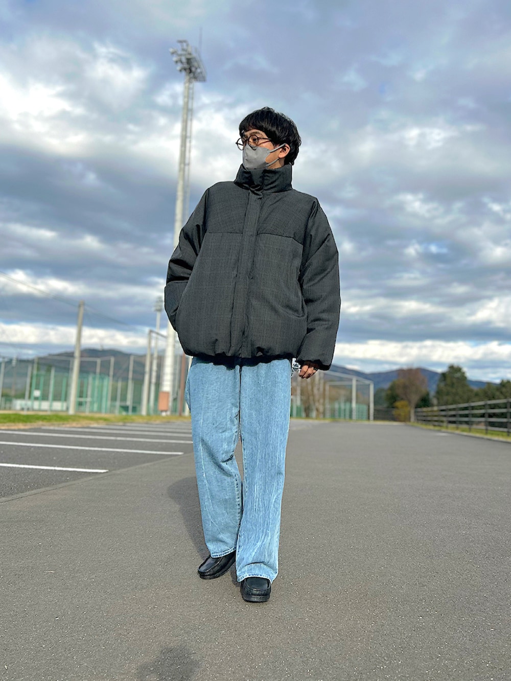 グレー系のダウンジャケット/コート、ブラック系のショルダーバッグ、ブルー系のデニムパンツを着用したメンズの冬コーディネートの2枚目の写真