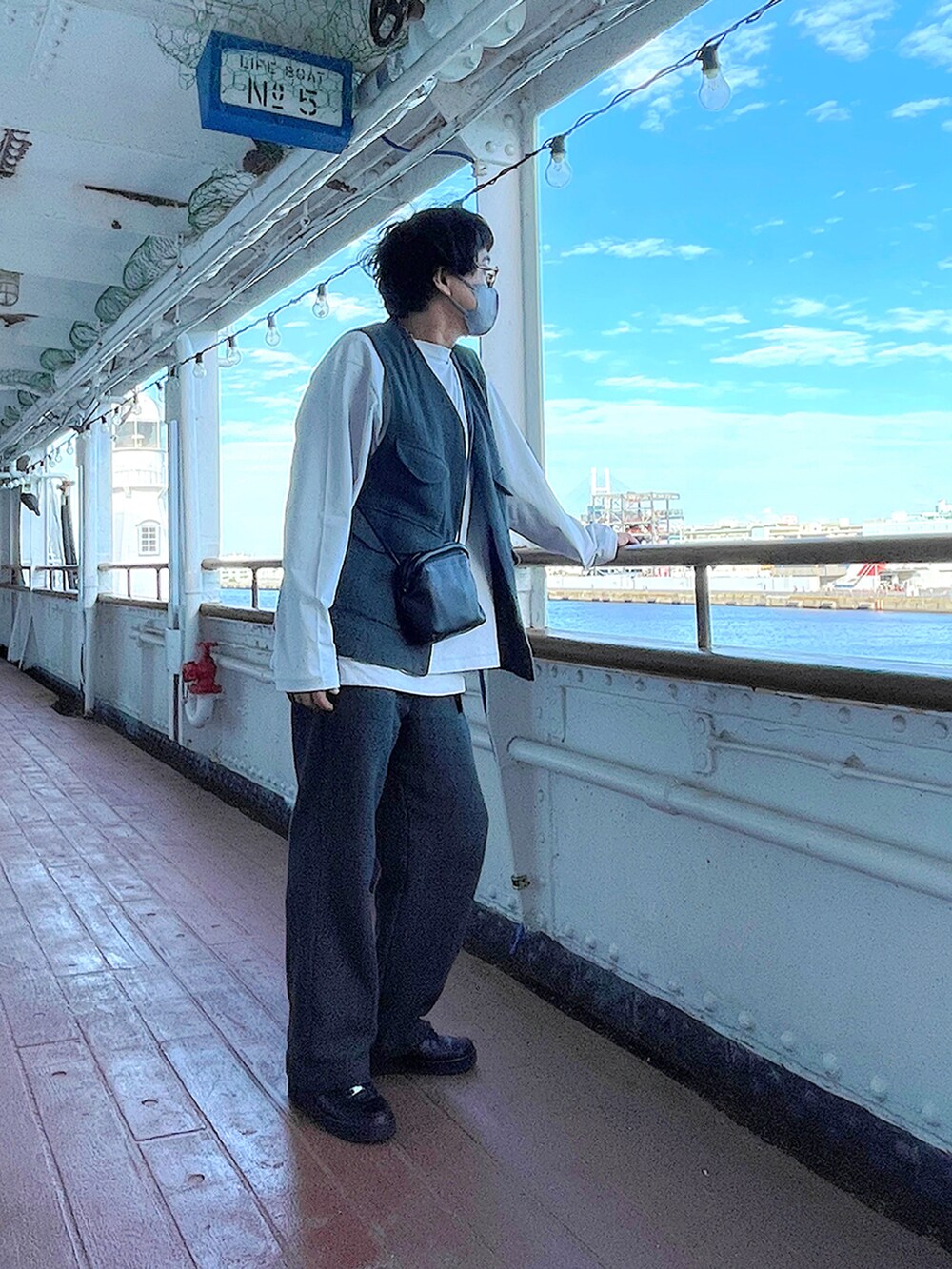 ホワイト系のTシャツ/カットソー、グレー系のベスト、ブラック系のショルダーバッグを着用したメンズの秋コーディネートの2枚目の写真