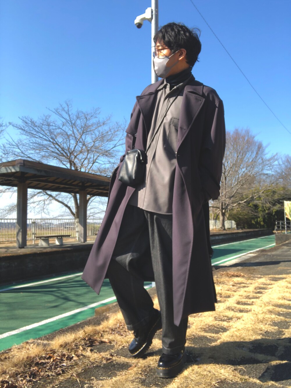 ブルー系のTシャツ/カットソー、グレー系のシャツ/ブラウス、グレー系のトレンチコートを着用したメンズの冬コーディネートの2枚目の写真