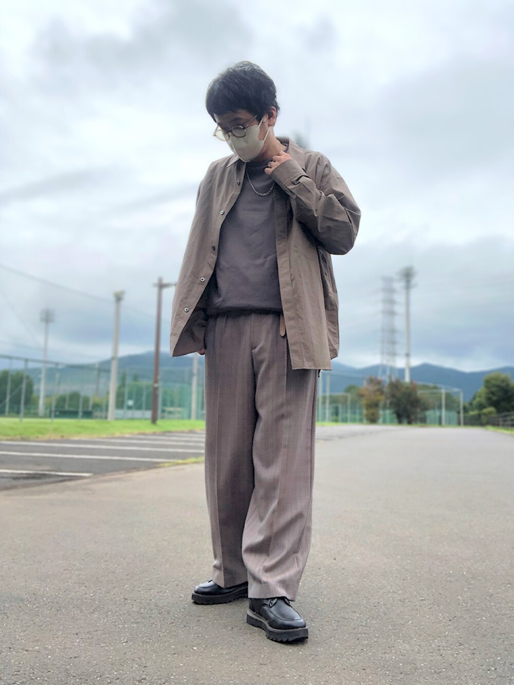 ブラウン系のシャツ/ブラウス、ブラウン系のTシャツ/カットソー、ベージュ系のスラックスを着用したメンズの秋コーディネートの2枚目の写真