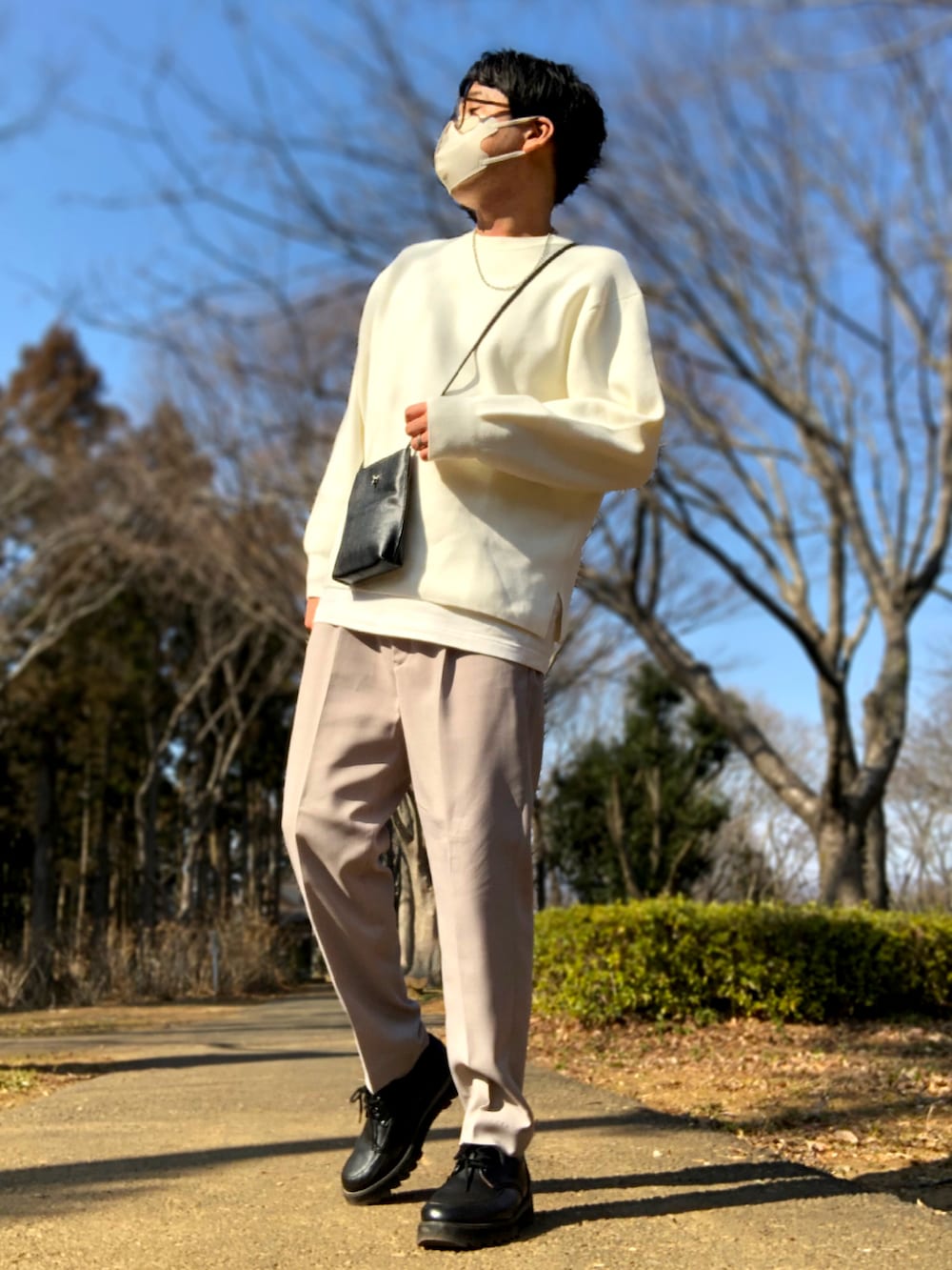 ベージュ系のセットアップ、ホワイト系のニット/セーター、ブラック系のショルダーバッグを着用したメンズの春コーディネートの2枚目の写真