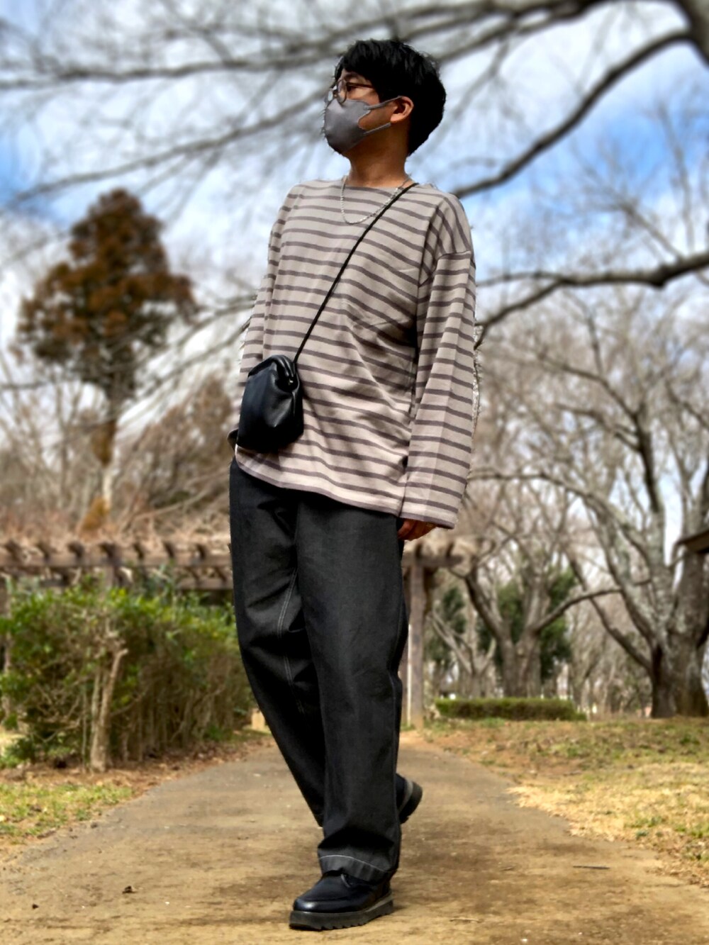 ブラック系のショルダーバッグ、グレー系のTシャツ/カットソー、グレー系のトレンチコートを着用したメンズの春コーディネートの2枚目の写真