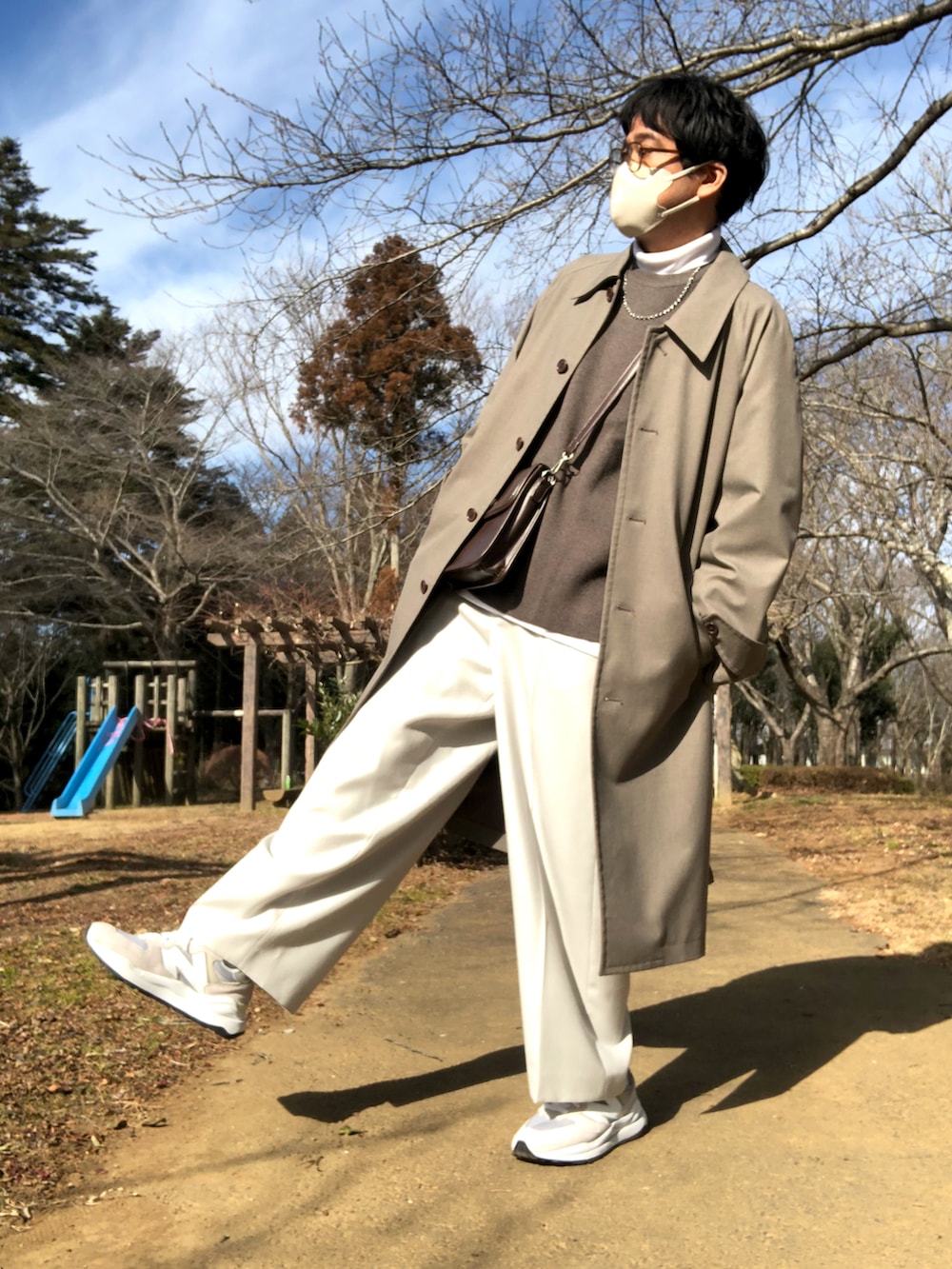 ホワイト系のTシャツ/カットソー、ブラウン系のニット/セーター、ブラウン系のステンカラーコートを着用したメンズの冬コーディネートの2枚目の写真