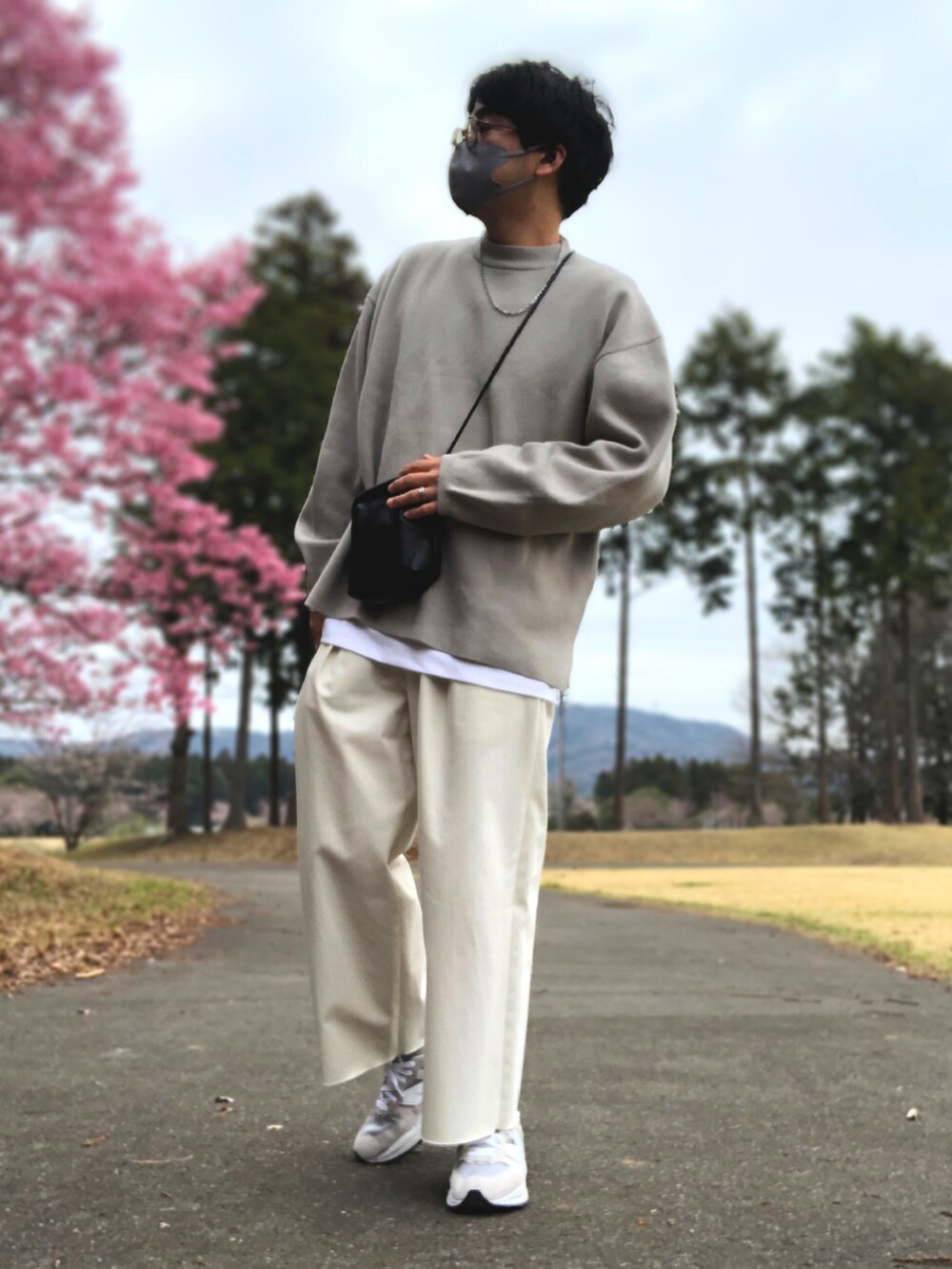 グレー系のブルゾン、ホワイト系のスラックス、グレー系のスニーカーを着用したメンズの春コーディネートの2枚目の写真