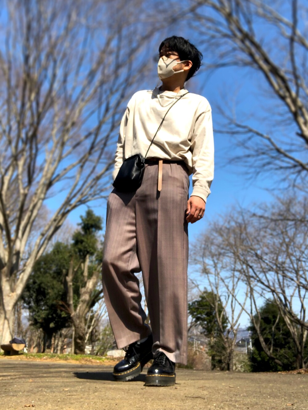 グレー系のトレンチコート、ブラック系のドレスシューズ、ブラック系のショルダーバッグを着用したメンズの春コーディネートの2枚目の写真