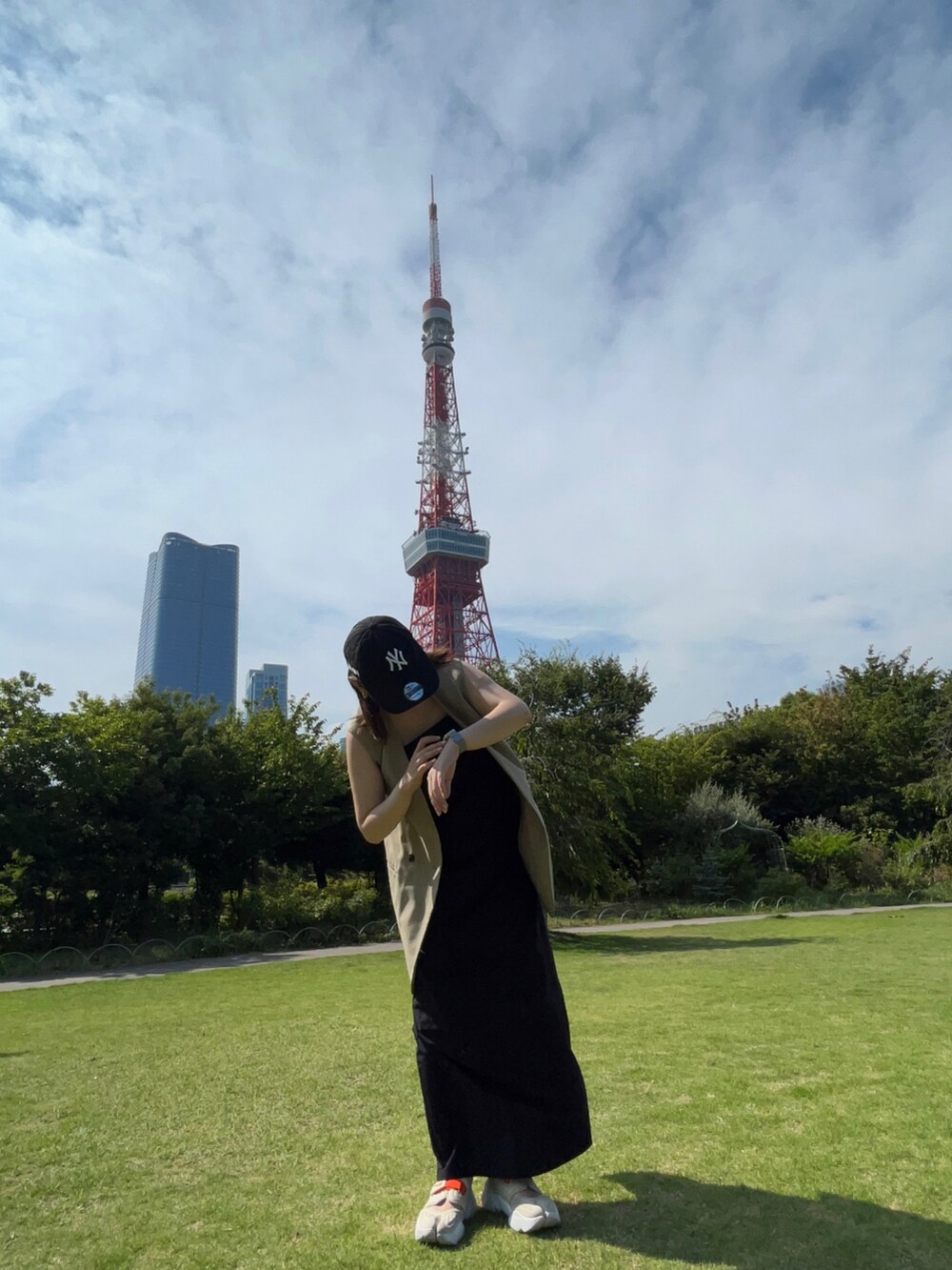 ブラック系のワンピース、ベージュ系のベスト、ベージュ系のサンダルを着用したレディースの夏コーディネートの2枚目の写真