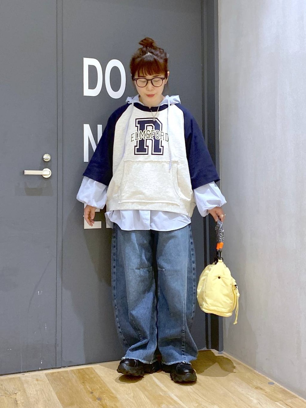 ブラック系のスニーカー、ブルー系のデニムパンツ、イエロー系のショルダーバッグを着用したレディースの春コーディネートの2枚目の写真