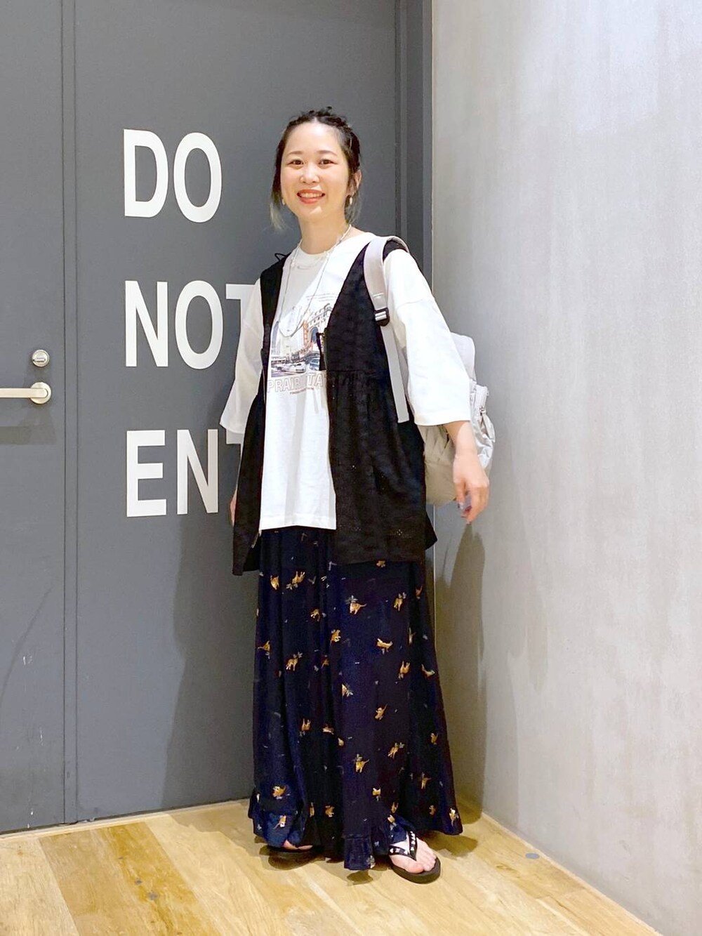 グレー系のバックパック/リュック、ブラック系のベスト、ホワイト系のTシャツ/カットソーを着用したレディースの夏コーディネートの2枚目の写真