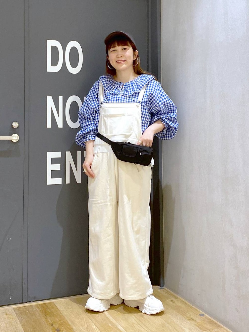 ベージュ系のスニーカー、ベージュ系のサロペット/オーバーオール、ブルー系のシャツ/ブラウスを着用したレディースの春コーディネートの2枚目の写真