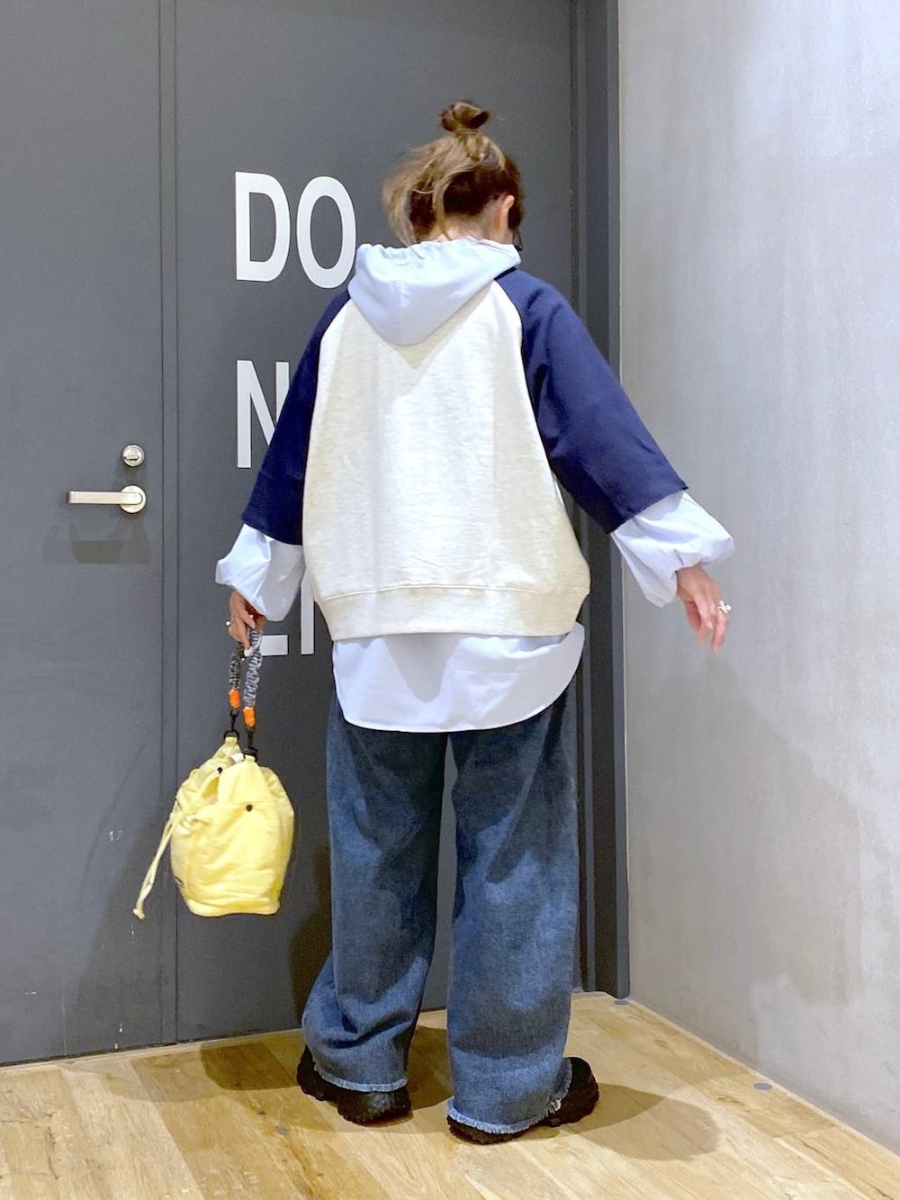 ブラック系のスニーカー、ブルー系のデニムパンツ、イエロー系のショルダーバッグを着用したレディースの春コーディネートの4枚目の写真