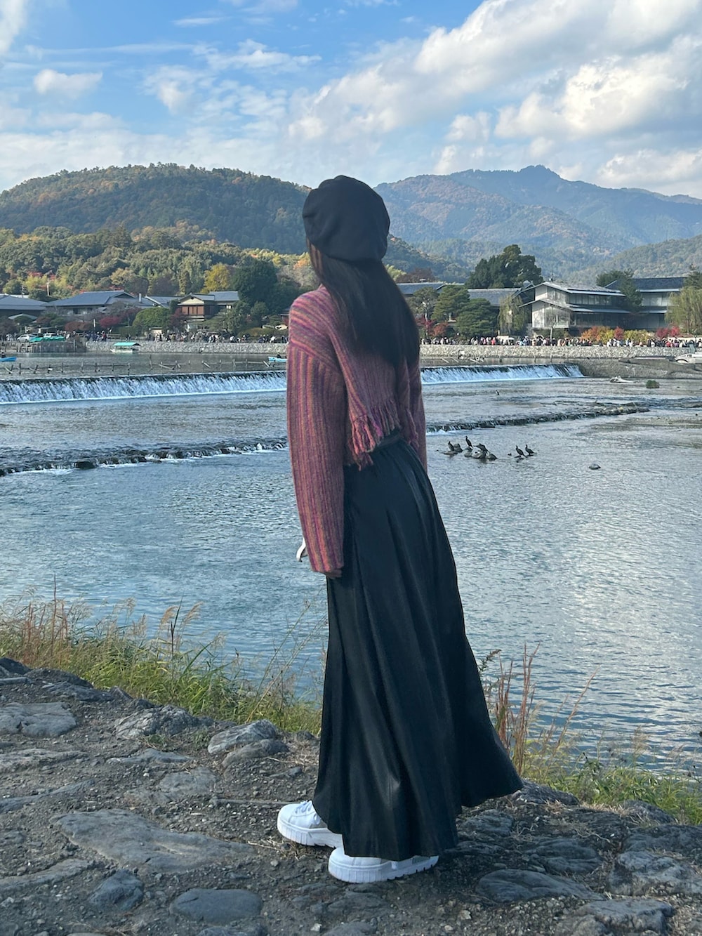 ピンク系のニット/セーター、ブラック系のスカート、ホワイト系のスニーカーを着用したレディースの秋コーディネートの2枚目の写真