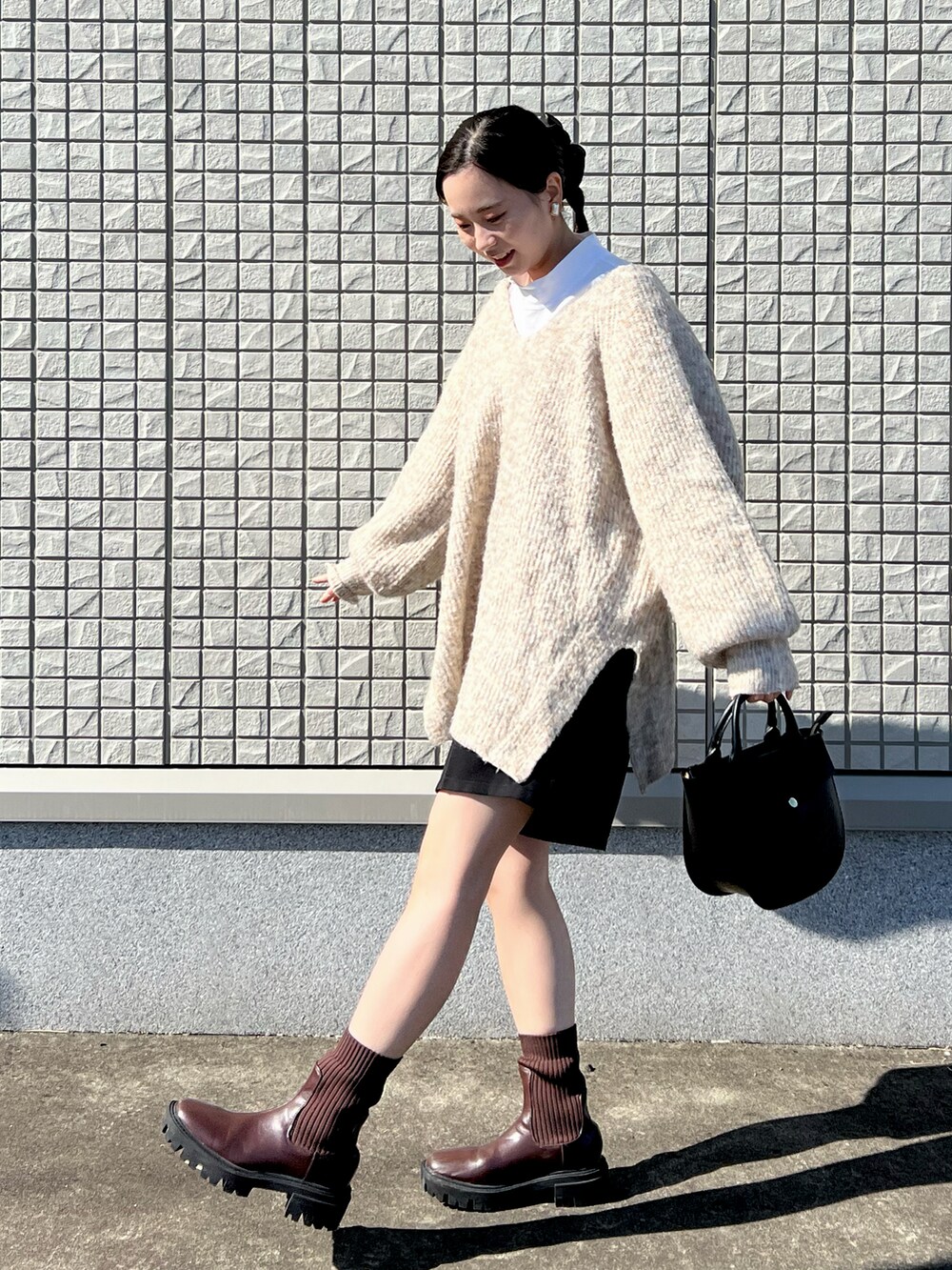 ホワイト系のニット/セーター、ホワイト系のTシャツ/カットソー、ブラック系のショルダーバッグを着用したレディースの秋コーディネートの2枚目の写真