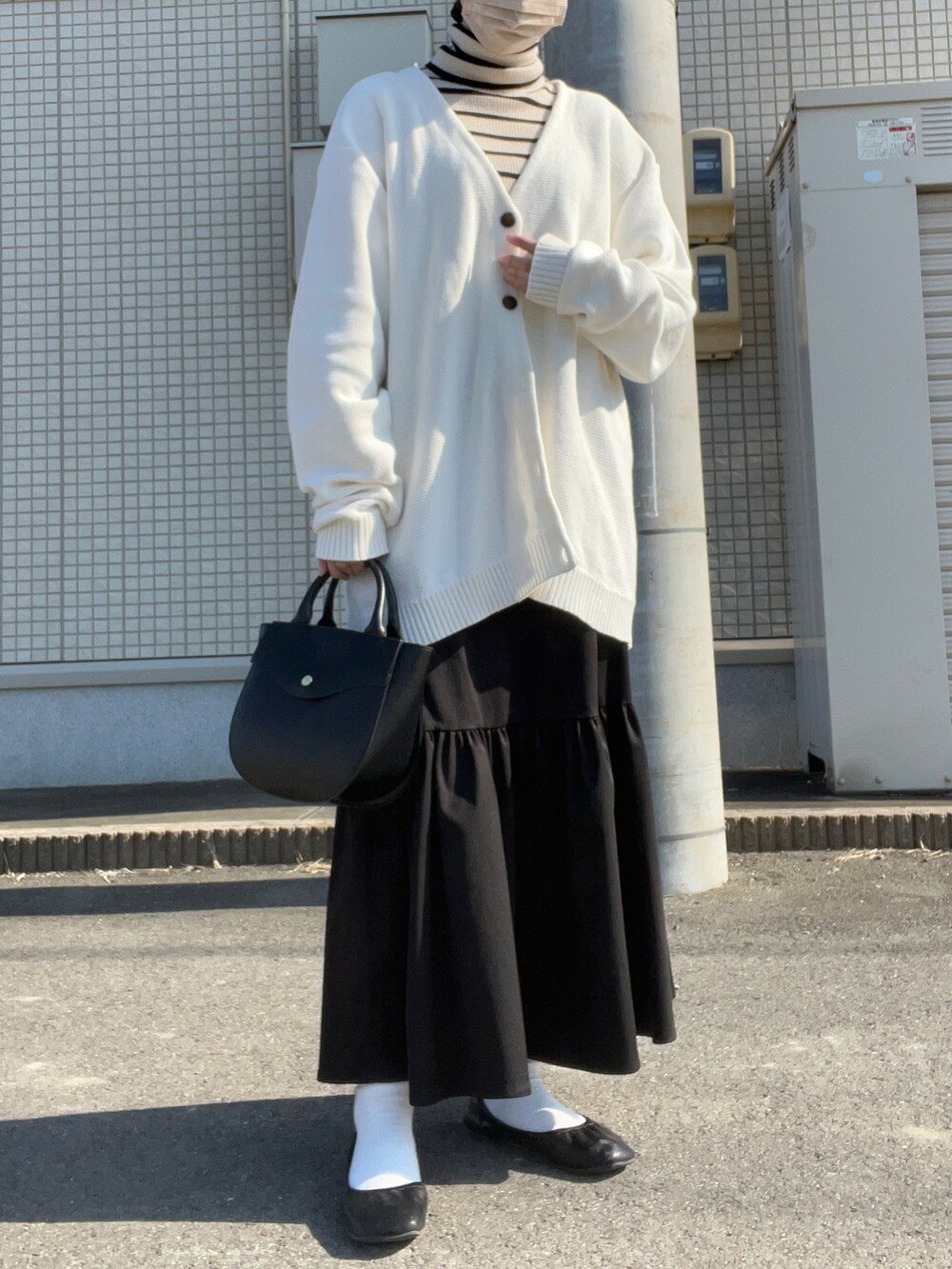 ホワイト系のカーディガン/ボレロ、ホワイト系のニット/セーター、ブラック系のスカートを着用したレディースの秋コーディネートの2枚目の写真