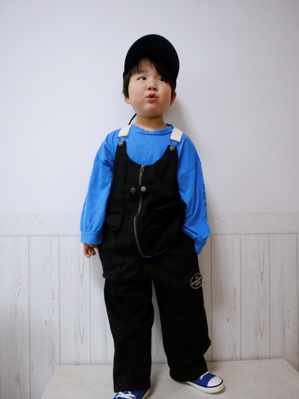 ブラック系のベスト、ブラック系のスウェットパンツ、ブルー系のスニーカーを着用したキッズの春コーディネートの2枚目の写真