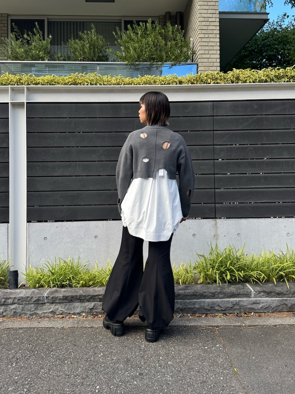 グレー系のニット/セーター、ホワイト系のシャツ/ブラウス、グレー系のその他パンツを着用したレディースの秋コーディネートの3枚目の写真