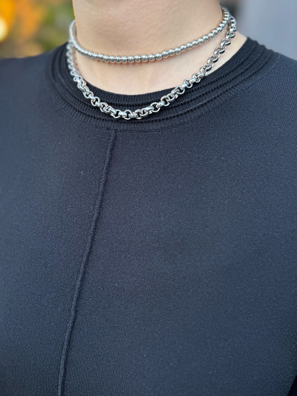 ブラック系のワンピース、シルバー系のブーツ、シルバー系のネックレスを着用したレディースの春コーディネートの6枚目の写真