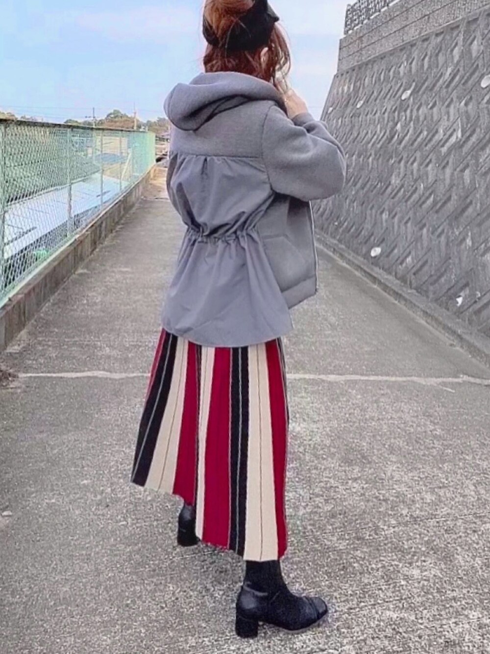 レッド系のスカート、グレー系のパーカー、ブラック系のヘアバンドを着用したレディースの秋コーディネートの3枚目の写真