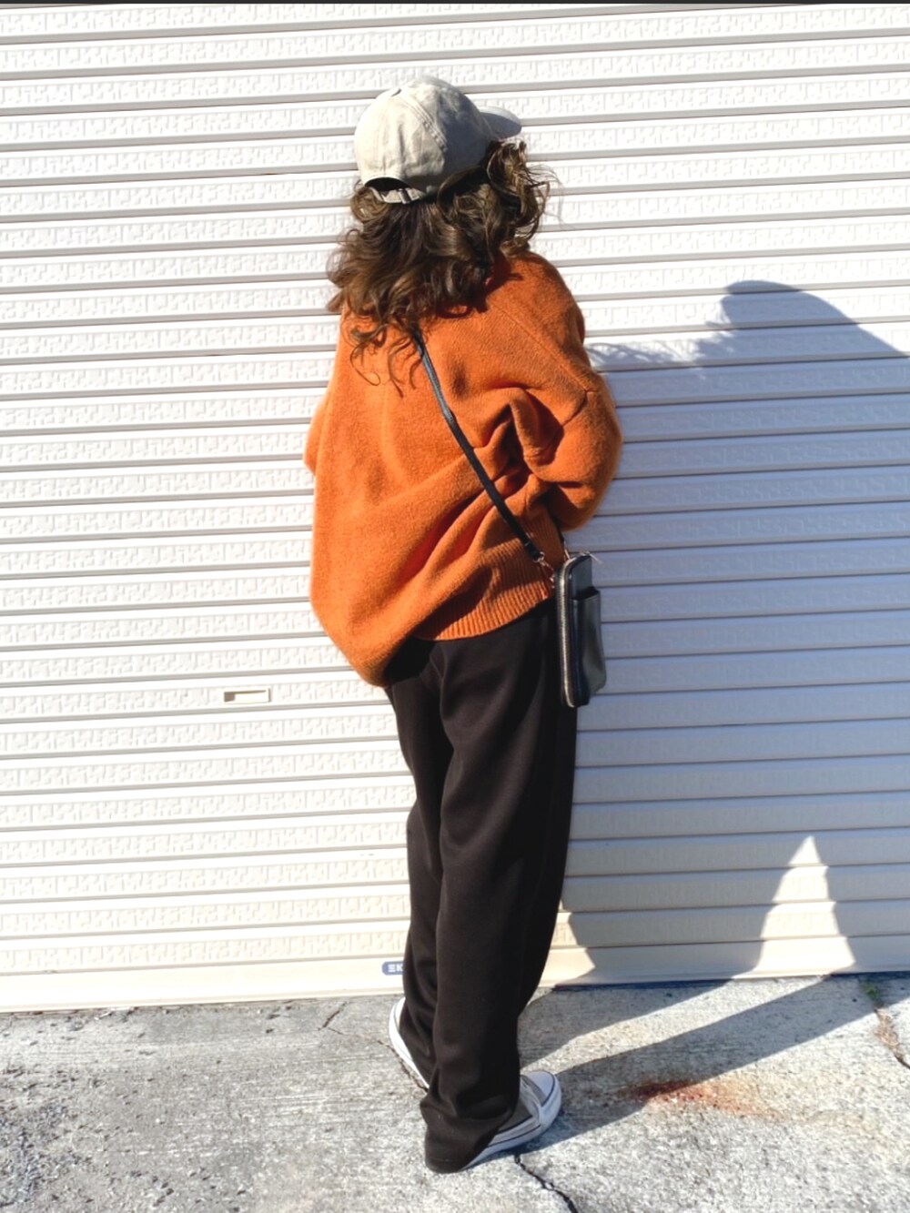 オレンジ系のニット/セーター、ブラック系のボディバッグ/ウエストポーチ、ブラウン系のスニーカーを着用したレディースの冬コーディネートの3枚目の写真