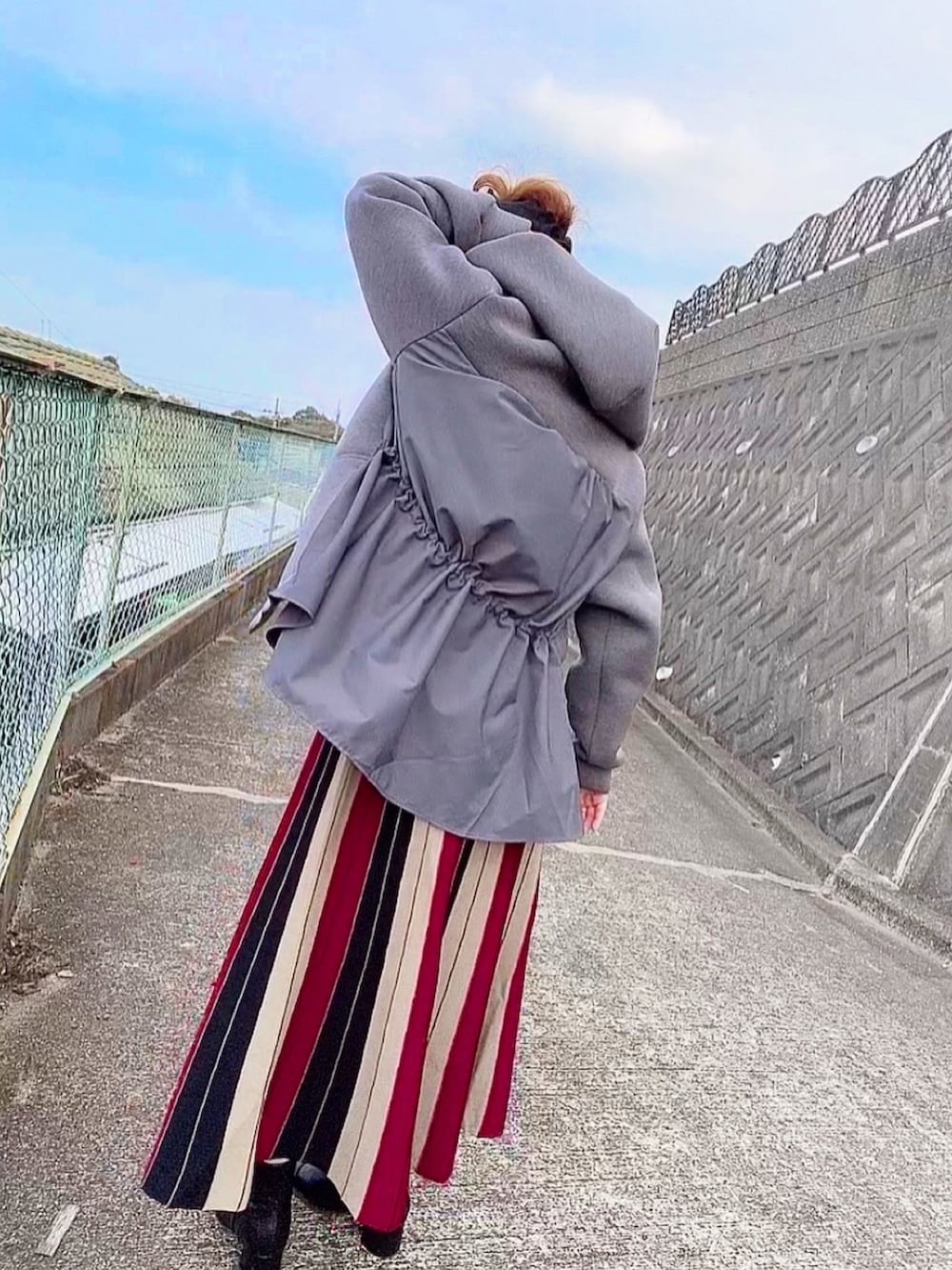 レッド系のスカート、グレー系のパーカー、ブラック系のヘアバンドを着用したレディースの秋コーディネートの2枚目の写真