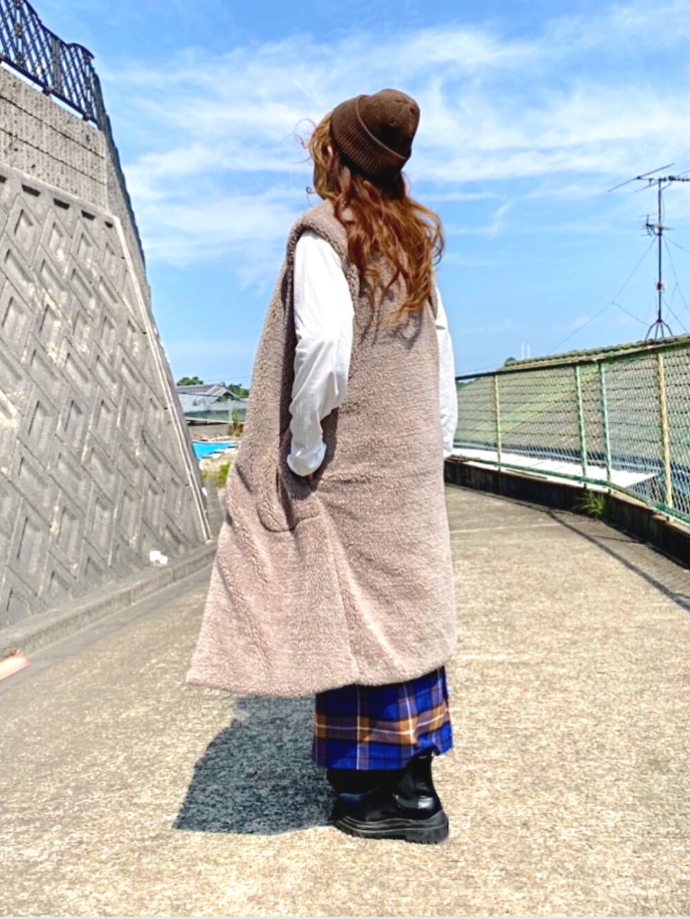 ブラウン系のベスト、ブルー系のスカート、ブラック系のボディバッグ/ウエストポーチを着用したレディースの秋コーディネートの3枚目の写真