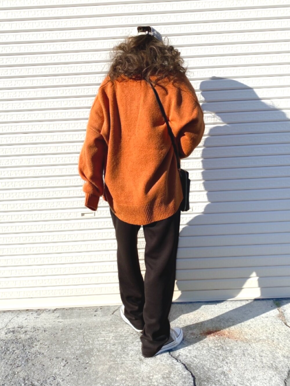 オレンジ系のニット/セーター、ブラック系のボディバッグ/ウエストポーチ、ブラウン系のスニーカーを着用したレディースの冬コーディネートの2枚目の写真