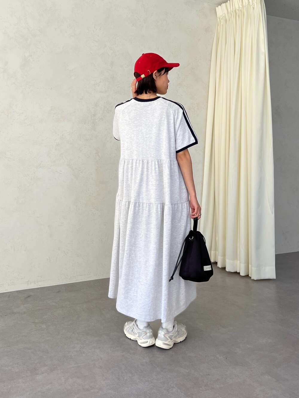 グレー系のワンピース、レッド系のキャップを着用したレディースの春コーディネートの4枚目の写真