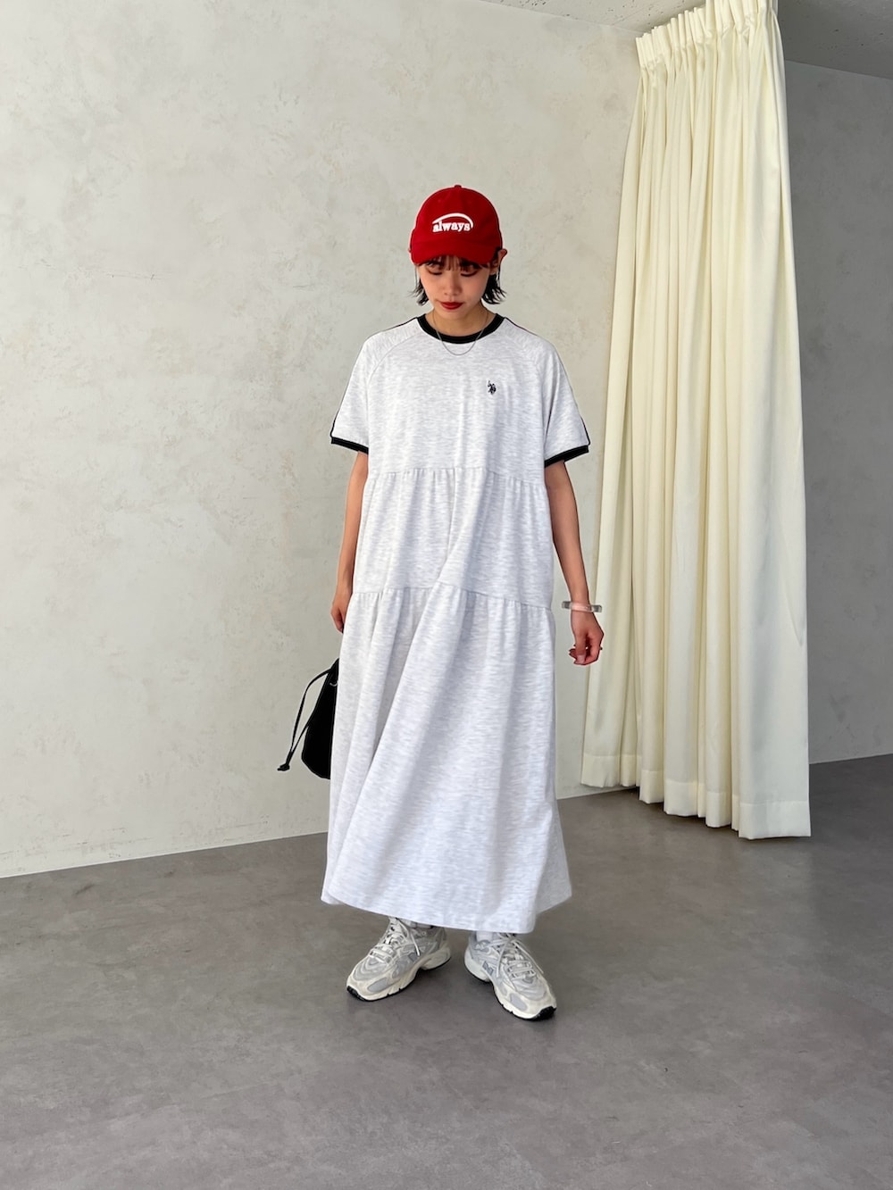 グレー系のワンピース、レッド系のキャップを着用したレディースの春コーディネートの2枚目の写真