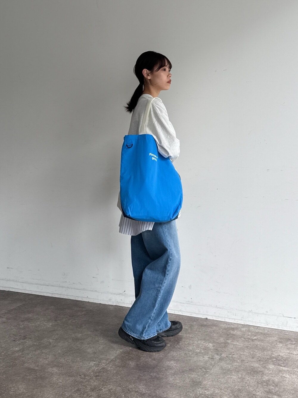 グレー系のTシャツ/カットソー、ホワイト系のシャツ/ブラウス、ブルー系のデニムパンツを着用したレディースの春コーディネートの2枚目の写真