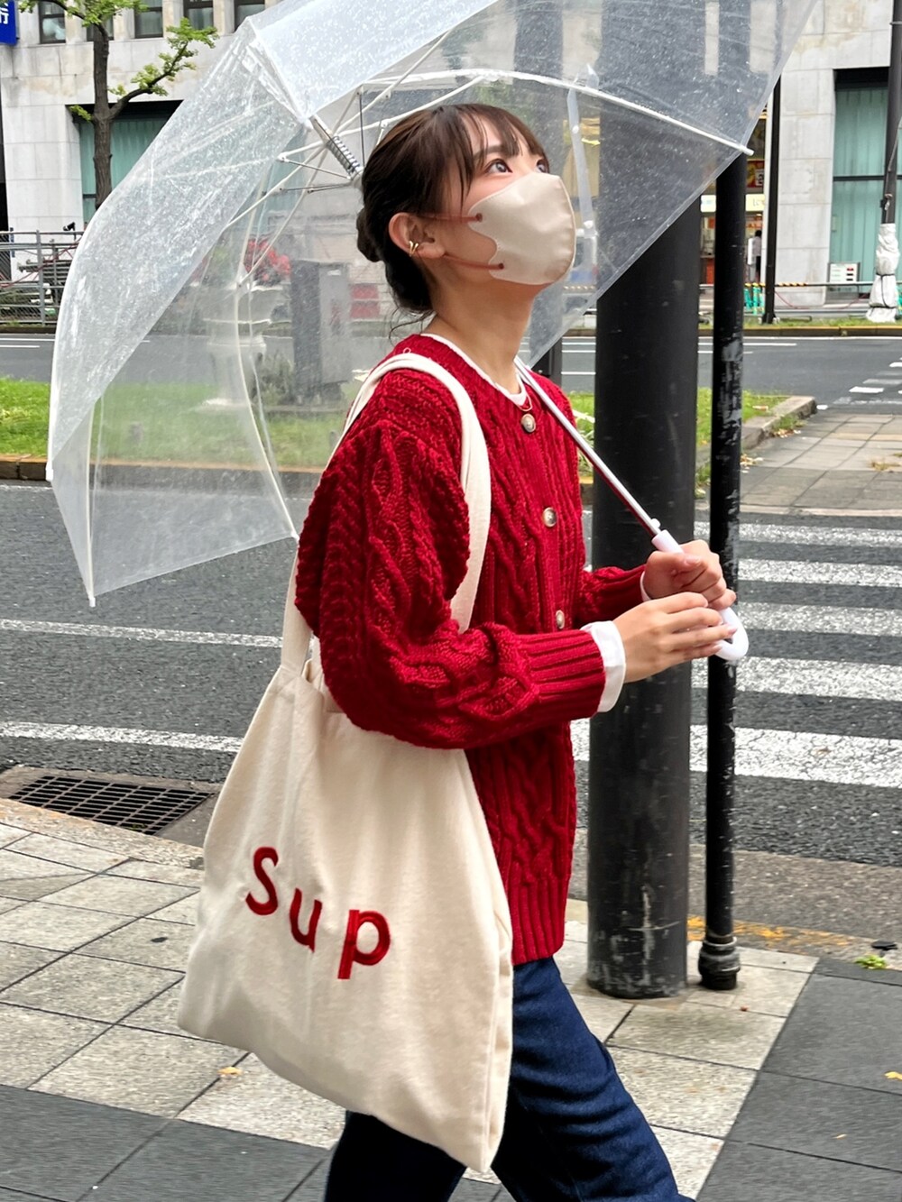 レッド系のカーディガン/ボレロ、ブルー系のデニムパンツ、ホワイト系のトートバッグを着用したレディースの秋コーディネートの2枚目の写真