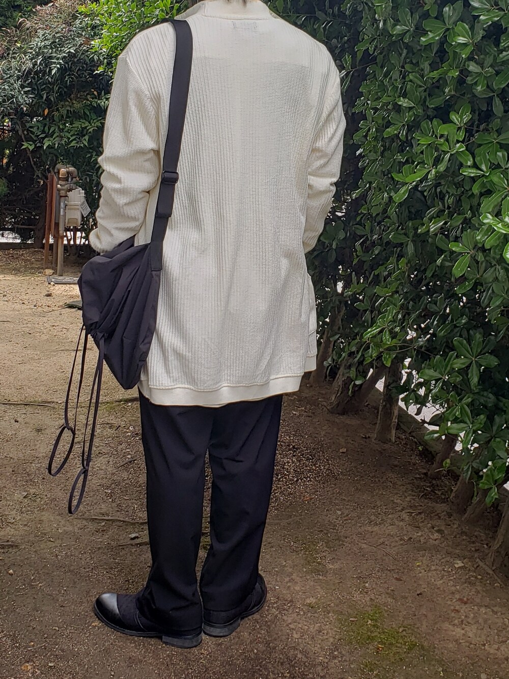 ホワイト系のニット/セーター、ブラック系のスラックス、ホワイト系のシャツ/ブラウスを着用したメンズの春コーディネートの3枚目の写真