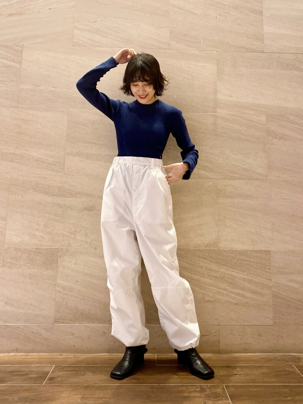ブルー系のニット/セーター、ホワイト系のその他パンツ、ブラック系のブーツを着用したレディースの冬コーディネートの2枚目の写真
