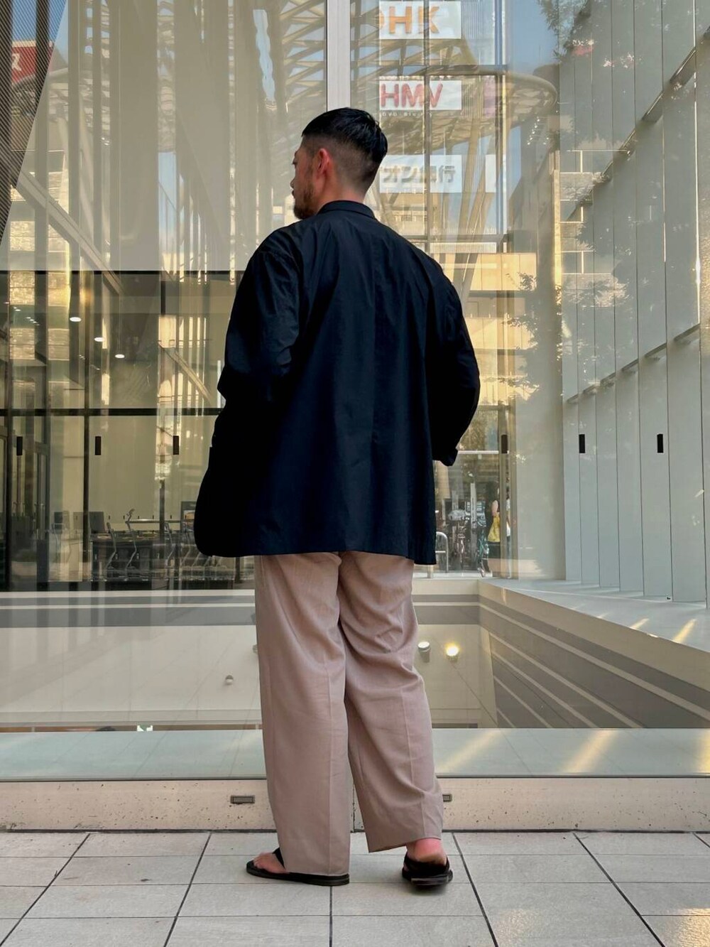 ブラック系のサンダル、ブラック系のその他アウター、ホワイト系のTシャツ/カットソーを着用したメンズの夏コーディネートの2枚目の写真