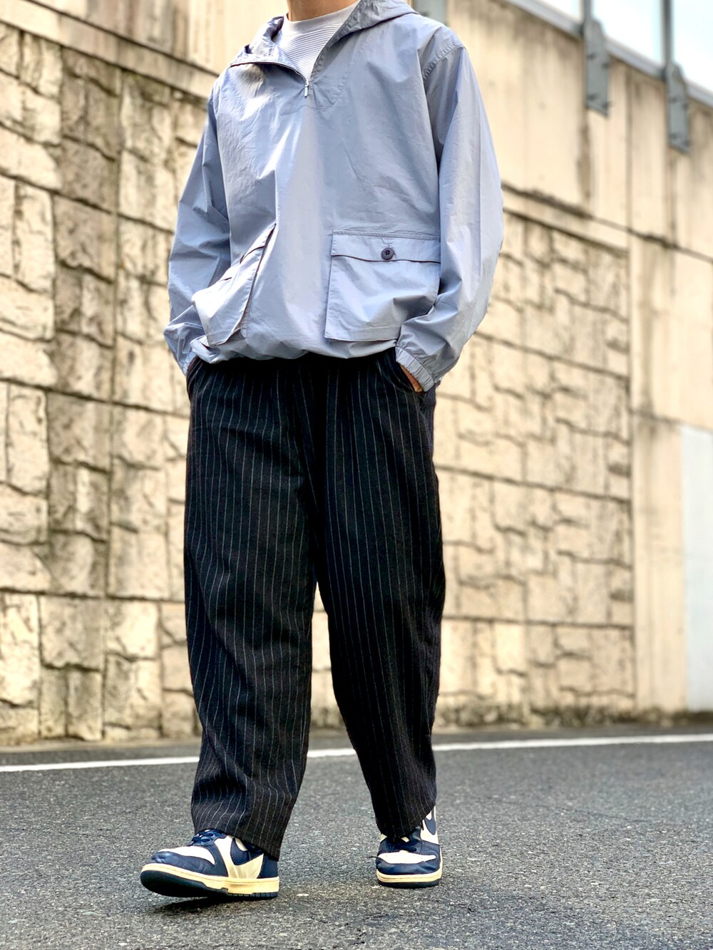 ブルー系のマウンテンパーカー、グレー系のステンカラーコート、ブラック系のスラックスを着用したメンズの春コーディネートの4枚目の写真