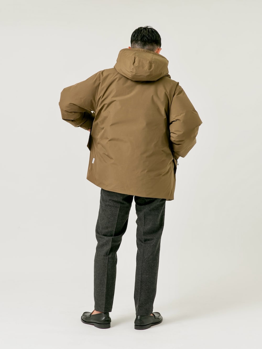 ブラウン系のダウンジャケット/コート、ブラック系のニット/セーター、グレー系のスラックスを着用したメンズの秋コーディネートの2枚目の写真