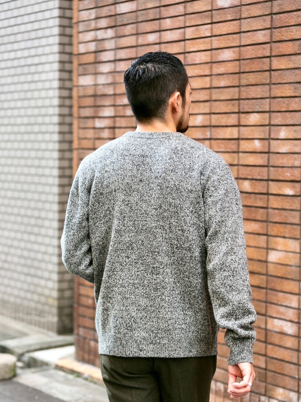 グレー系のニット/セーター、グリーン系のスラックス、ホワイト系のスニーカーを着用したメンズの冬コーディネートの3枚目の写真