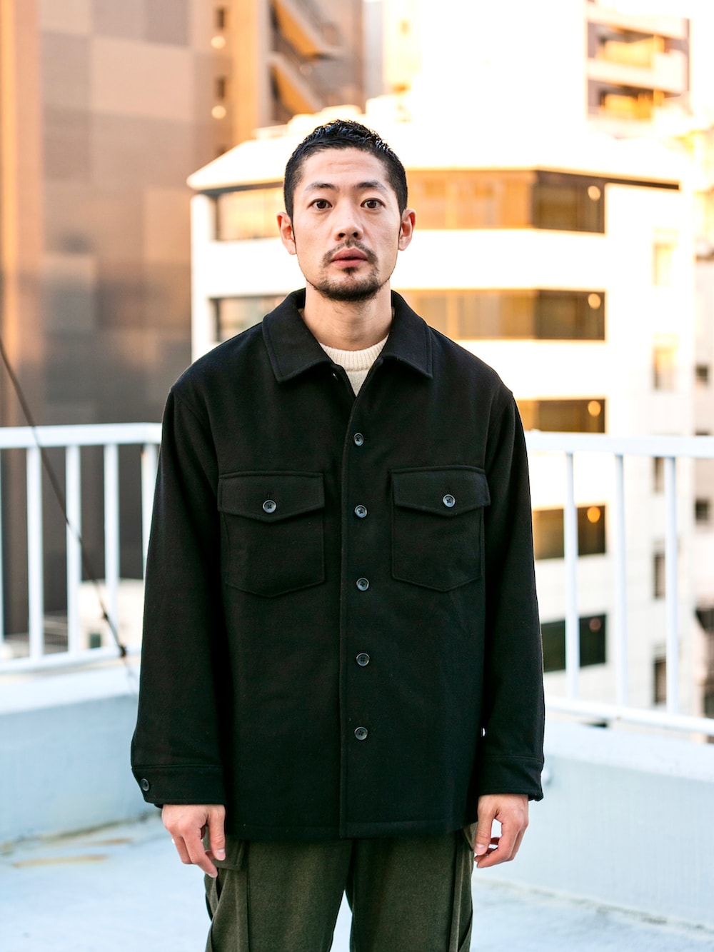 グリーン系のカーゴパンツ、ブラック系のその他アウター、ベージュ系のニット/セーターを着用したメンズの冬コーディネートの2枚目の写真