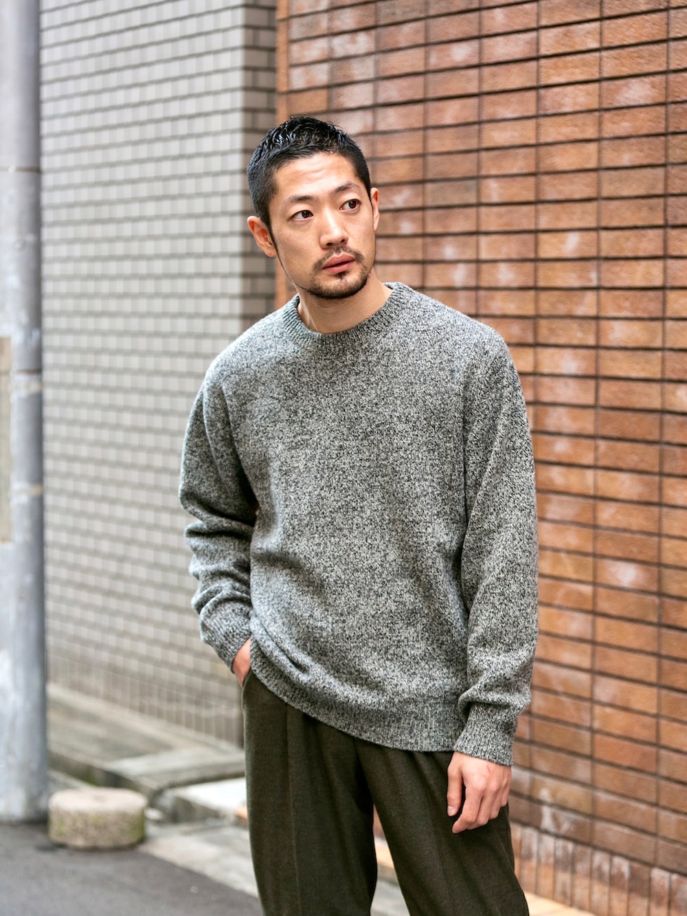 グレー系のニット/セーター、グリーン系のスラックス、ホワイト系のスニーカーを着用したメンズの冬コーディネートの2枚目の写真