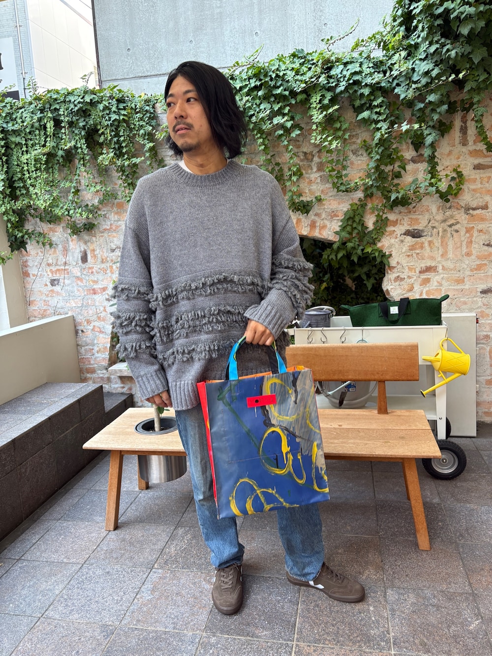 グレー系のニット/セーター、ブラウン系のスニーカーを着用したメンズの秋コーディネートの3枚目の写真