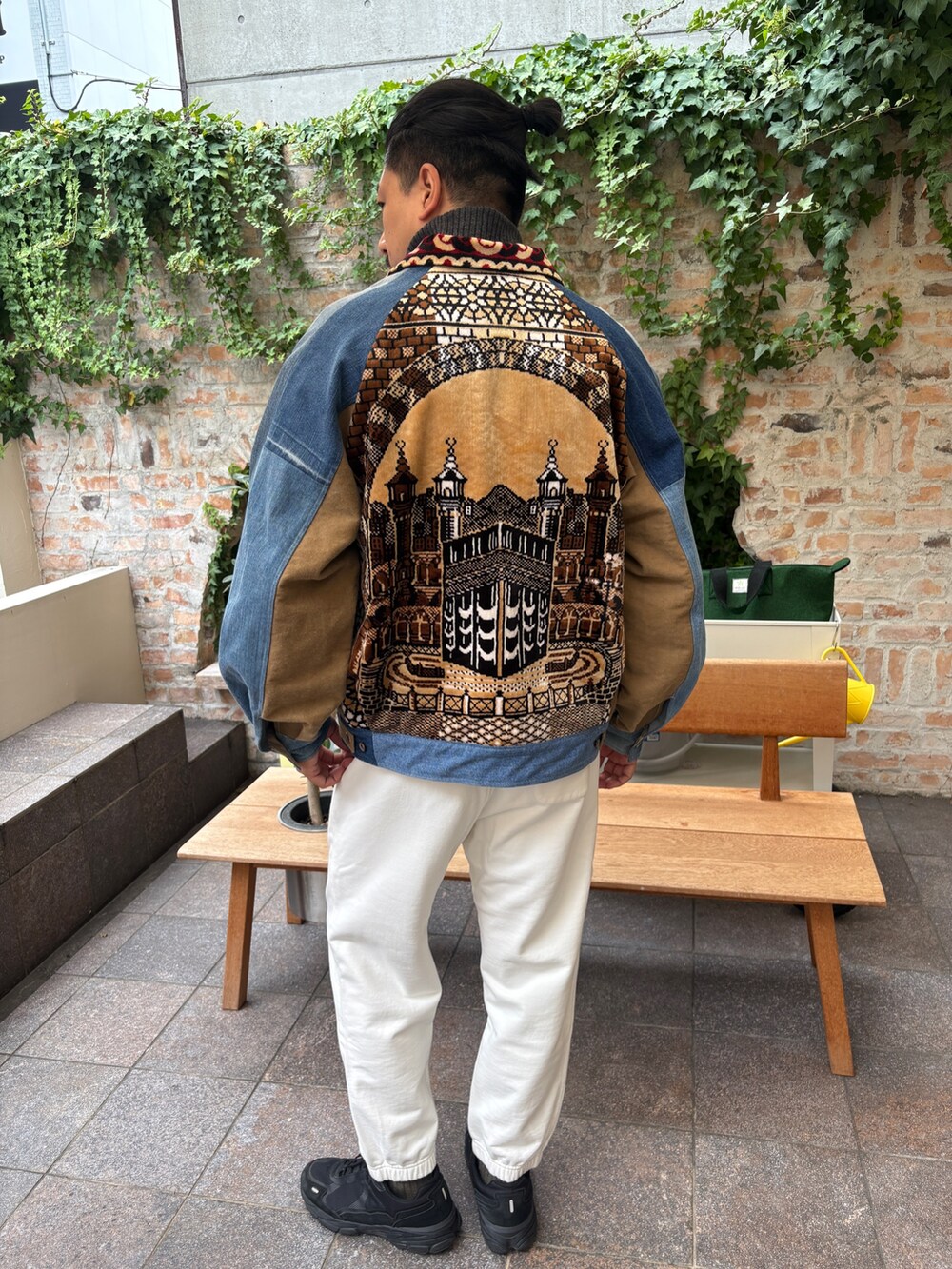 ブルー系のデニムジャケット、ブラック系のニット/セーター、ホワイト系のその他パンツを着用したメンズの秋コーディネートの2枚目の写真