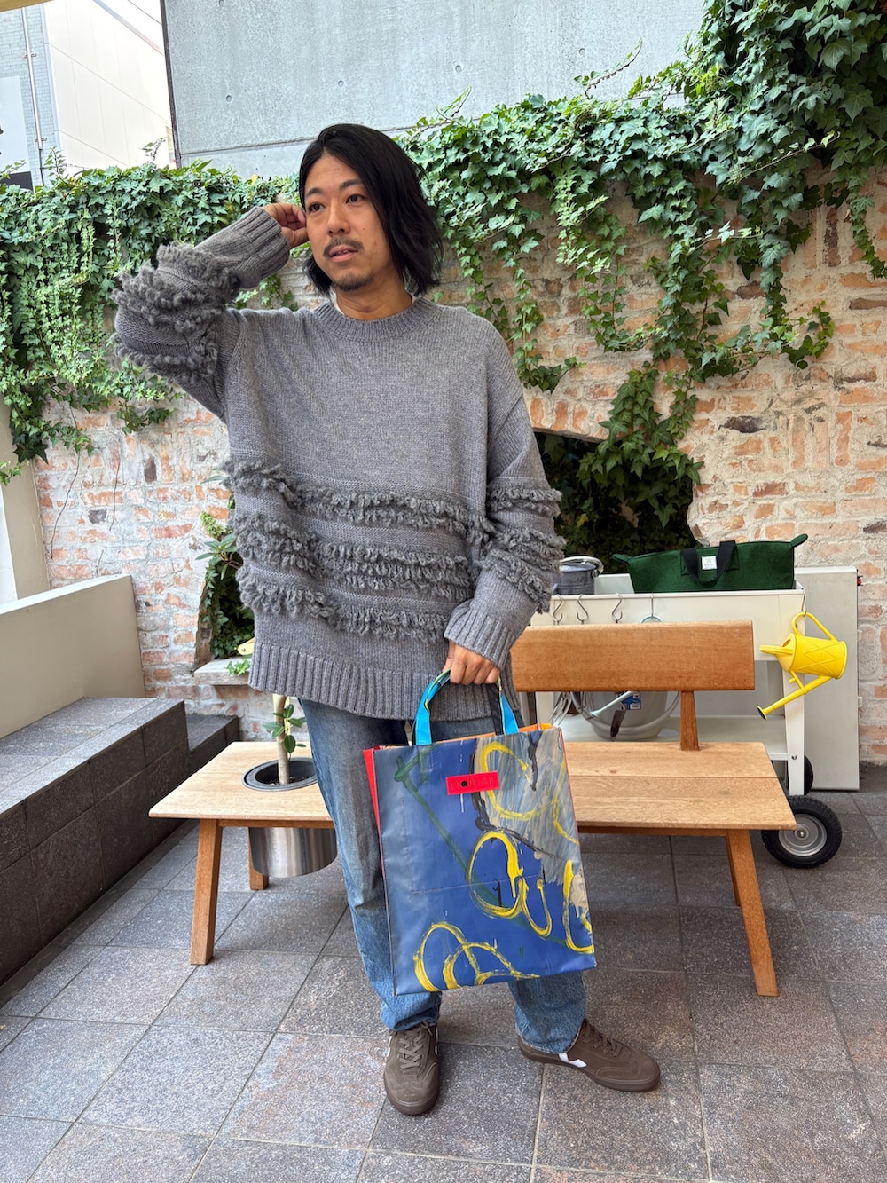 グレー系のニット/セーター、ブラウン系のスニーカーを着用したメンズの秋コーディネートの2枚目の写真